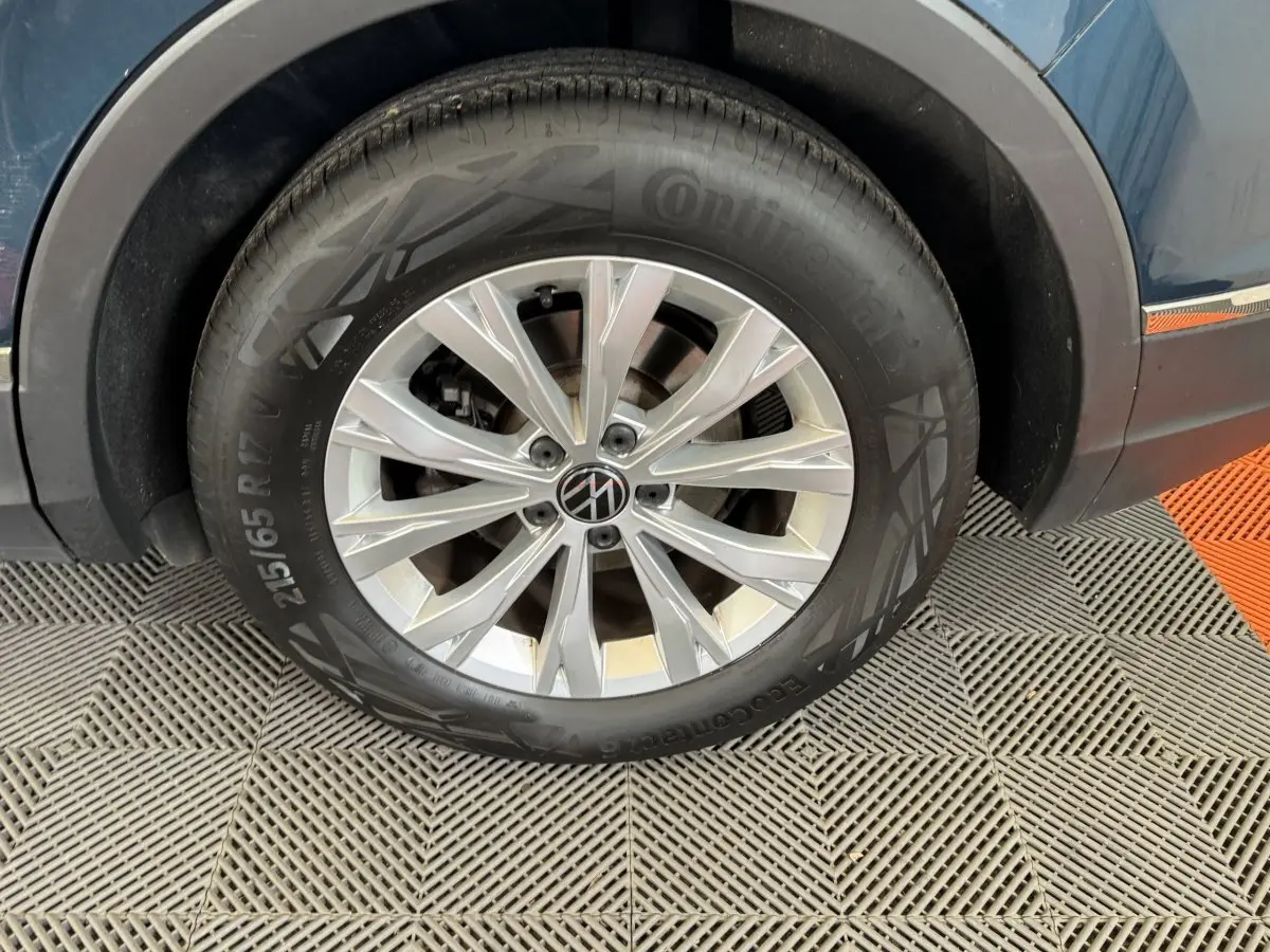 Gros plan sur la roue avant droite du Volkswagen Tiguan bleu, avec jante alliage argentée et pneu Continental.
