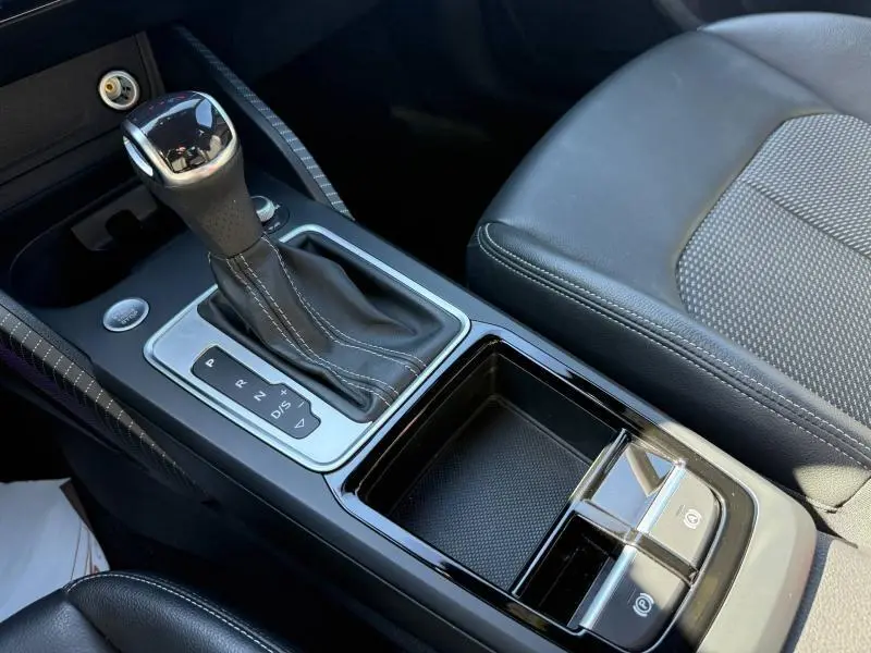 Gros plan sur la console centrale de l'Audi Q2 35 TDI S line 2025 avec levier de vitesse automatique et sellerie noire.