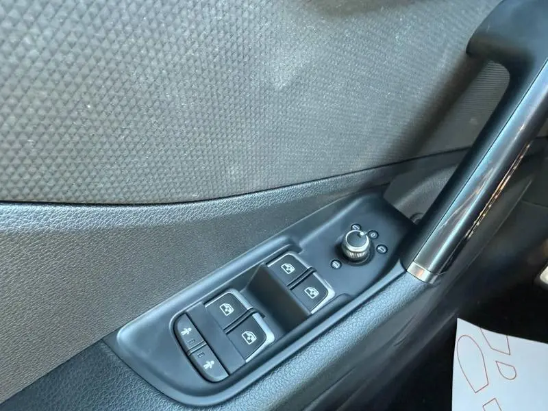 Gros plan sur les commandes des vitres et rétroviseurs côté conducteur de l'Audi Q2 35 TDI S line 2025, finition noire.