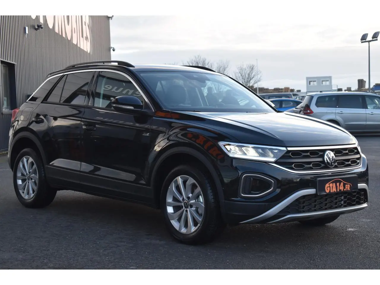 Volkswagen T-Roc 2025 noir grenadilla, vue 3/4 avant droit avec jantes alliage 17 pouces et feux LED allumés.