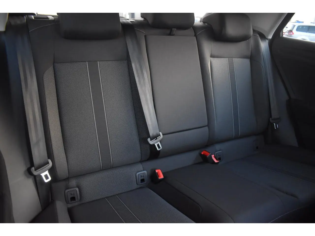 Vue intérieure sur les sièges arrière en tissu noir du Volkswagen T-Roc 2025, avec ceintures de sécurité visibles.