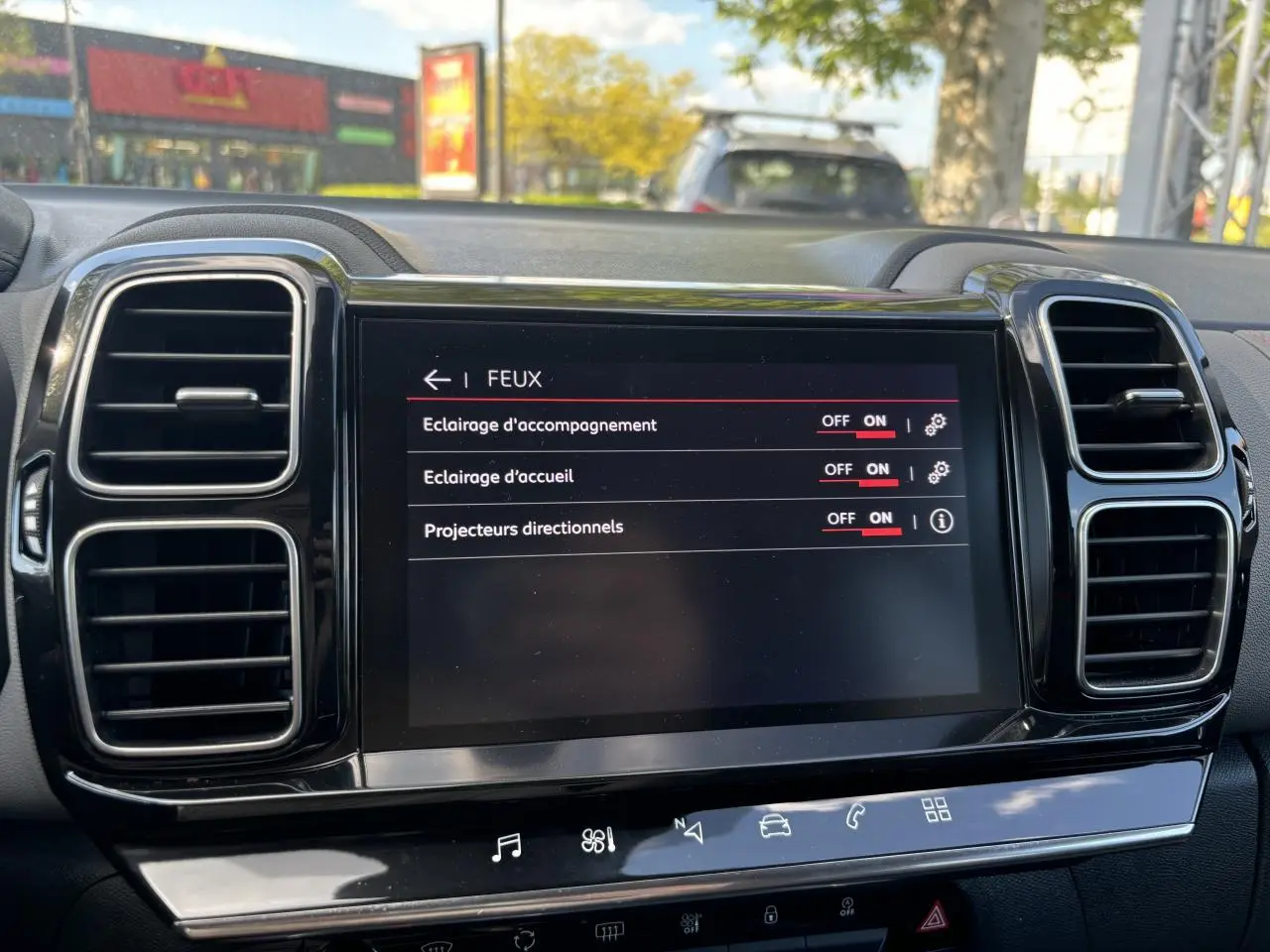 Écran tactile central du tableau de bord du Citroën C5 Aircross 2019, affichant les réglages des feux, entouré de grilles d'aération noires.
