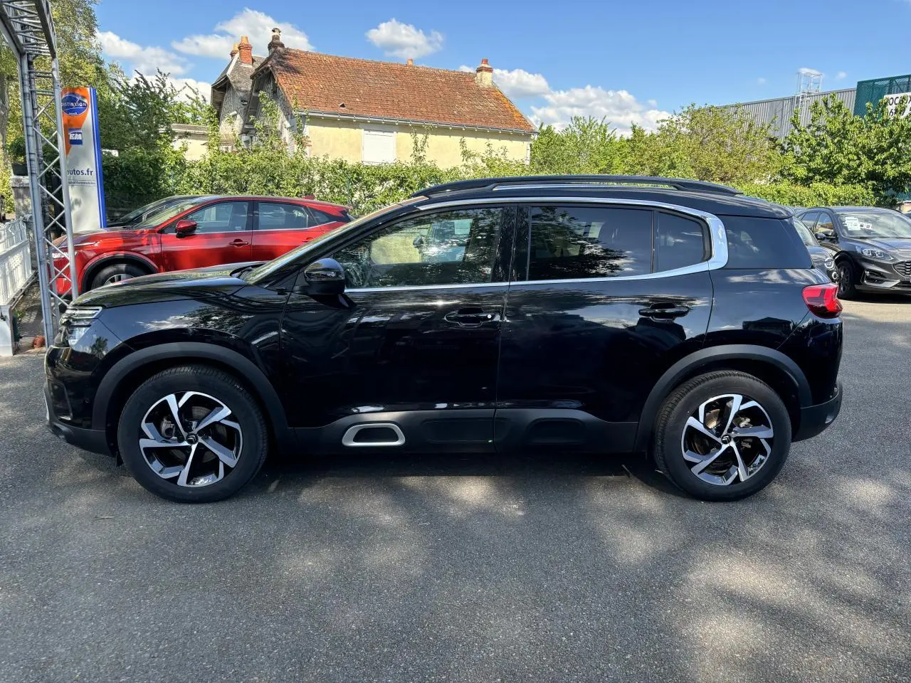 Profil côté gauche d'un Citroën C5 Aircross noir métallisé, avec ses jantes distinctives et ses vitres surteintées.