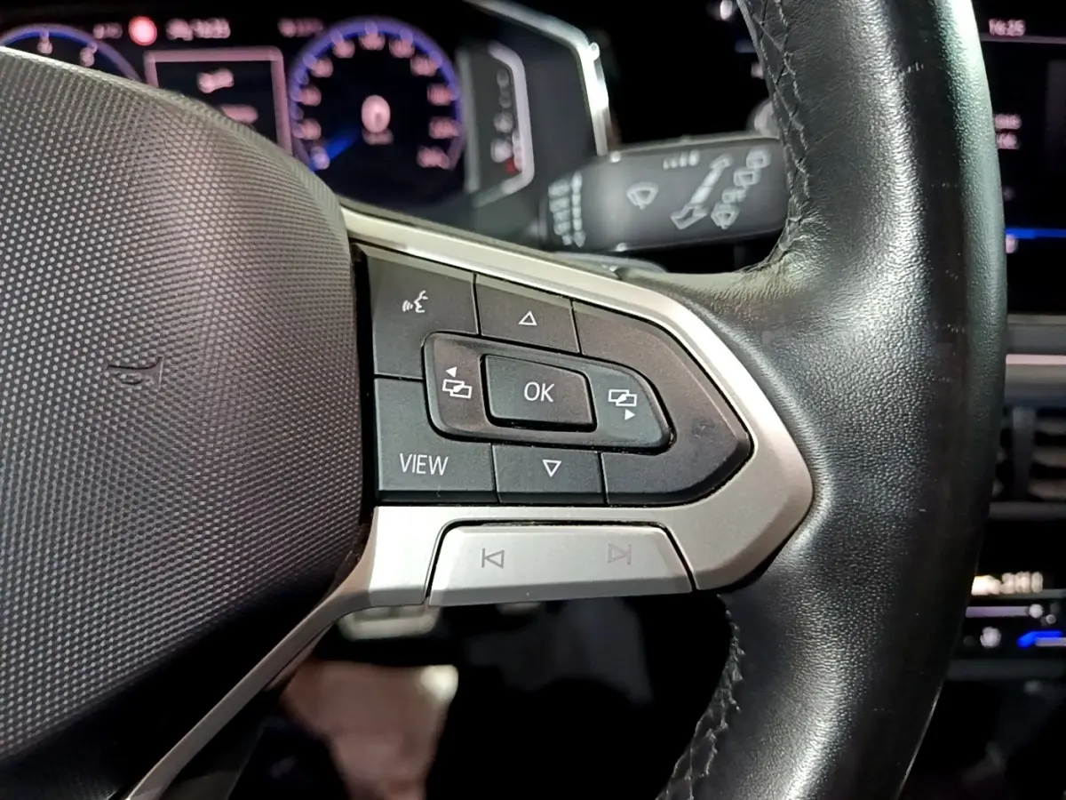 Gros plan sur le volant en cuir noir du Volkswagen Taigo 1.0 TSI 110 DSG R-Line avec commandes multifonctions et affichage digital.