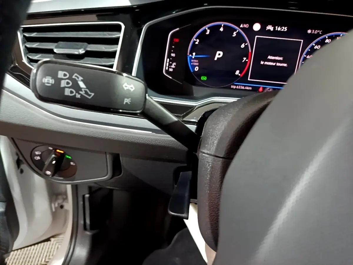 Vue rapprochée du tableau de bord et du volant de la Volkswagen Taigo blanc, avec affichage digital et commandes au volant visibles.