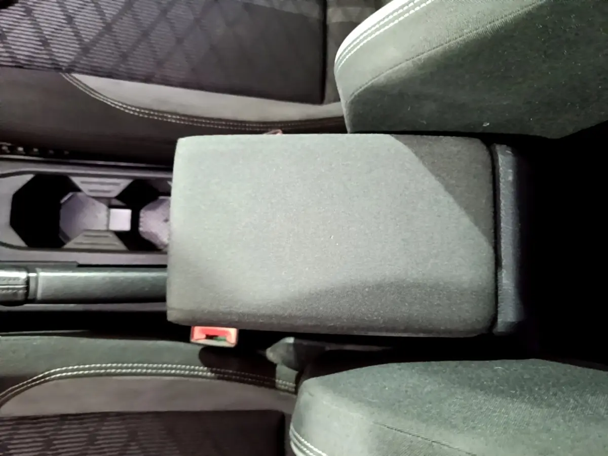 Vue plongeante sur l'accoudoir central noir et les sièges avant en tissu du Volkswagen Taigo blanc 2022.