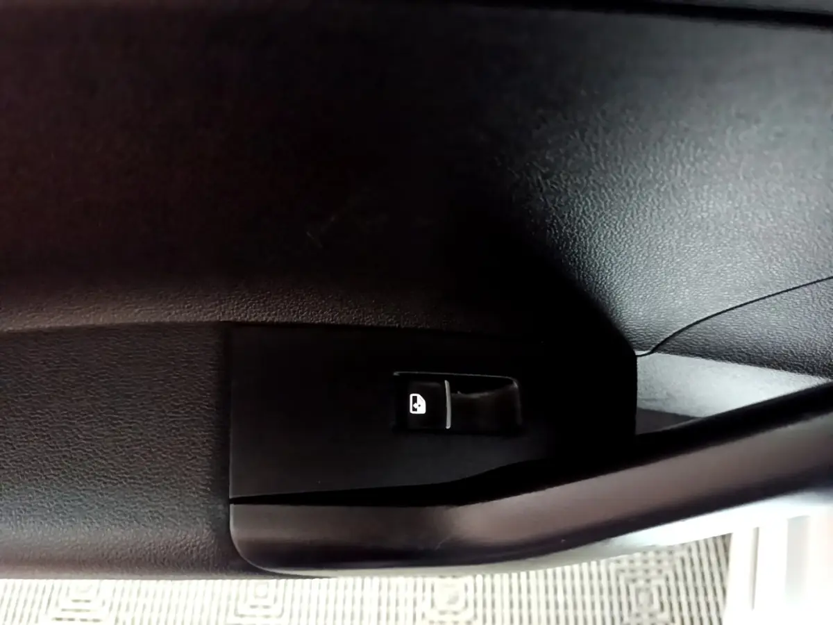 Gros plan sur le levier d'ouverture de trappe à carburant noir à l'intérieur d'un Volkswagen Taigo blanc.