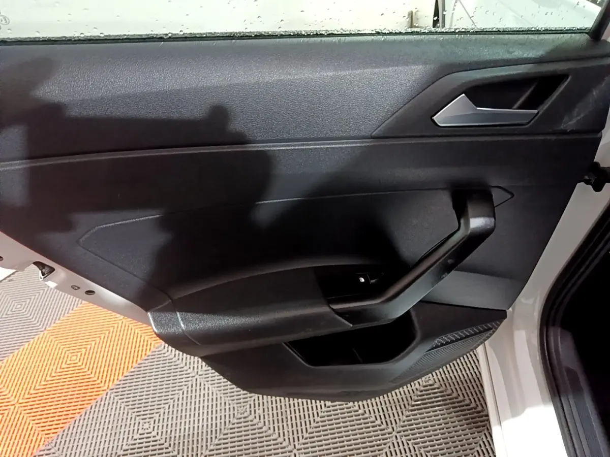 Vue intérieure côté gauche de la porte avant noire du Volkswagen Taigo blanc, avec poignée et bouton de verrouillage intégré.
