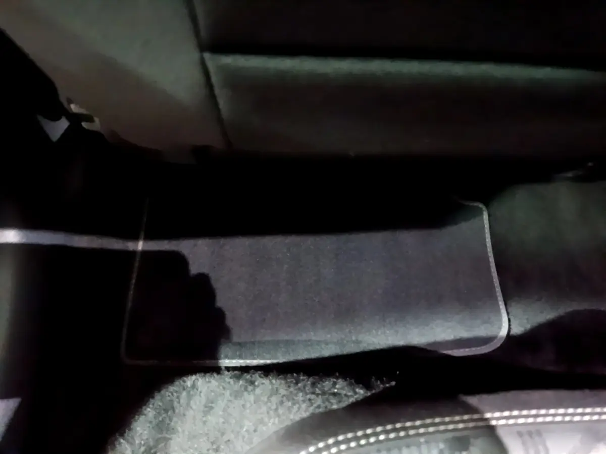 Vue intérieure du plancher arrière côté droit avec tapis noir et partie inférieure des sièges du Volkswagen Taigo blanc.