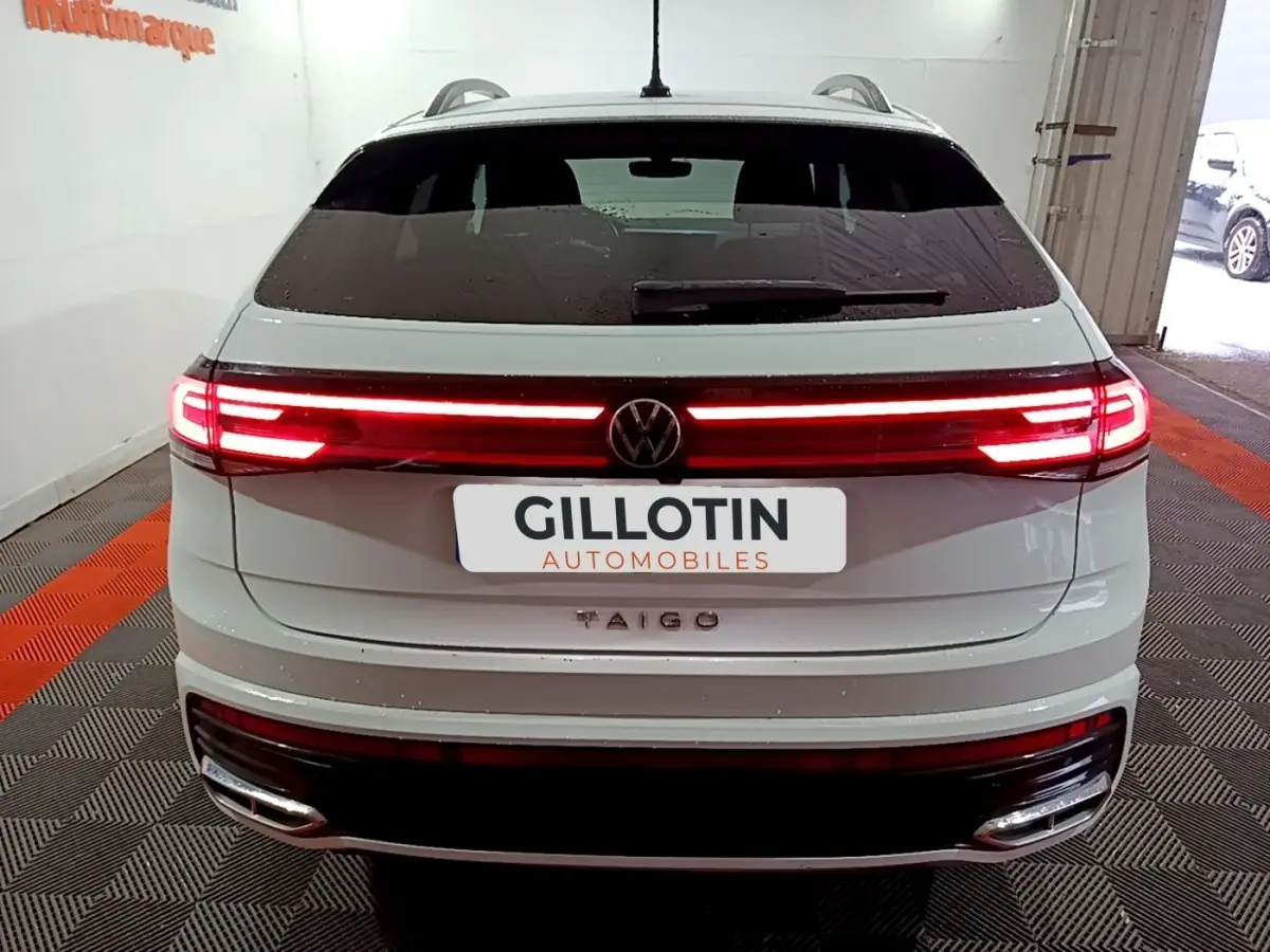 Vue arrière d’un Volkswagen Taigo blanc 2022 avec feux LED allumés et logo VW centré sur le hayon.