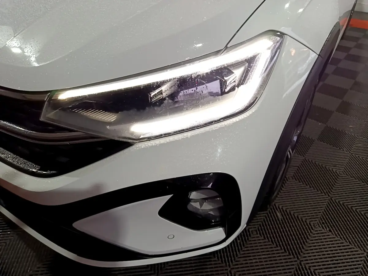 Gros plan sur le phare avant droit blanc du Volkswagen Taigo 2022 avec éclairage LED et antibrouillard intégré.