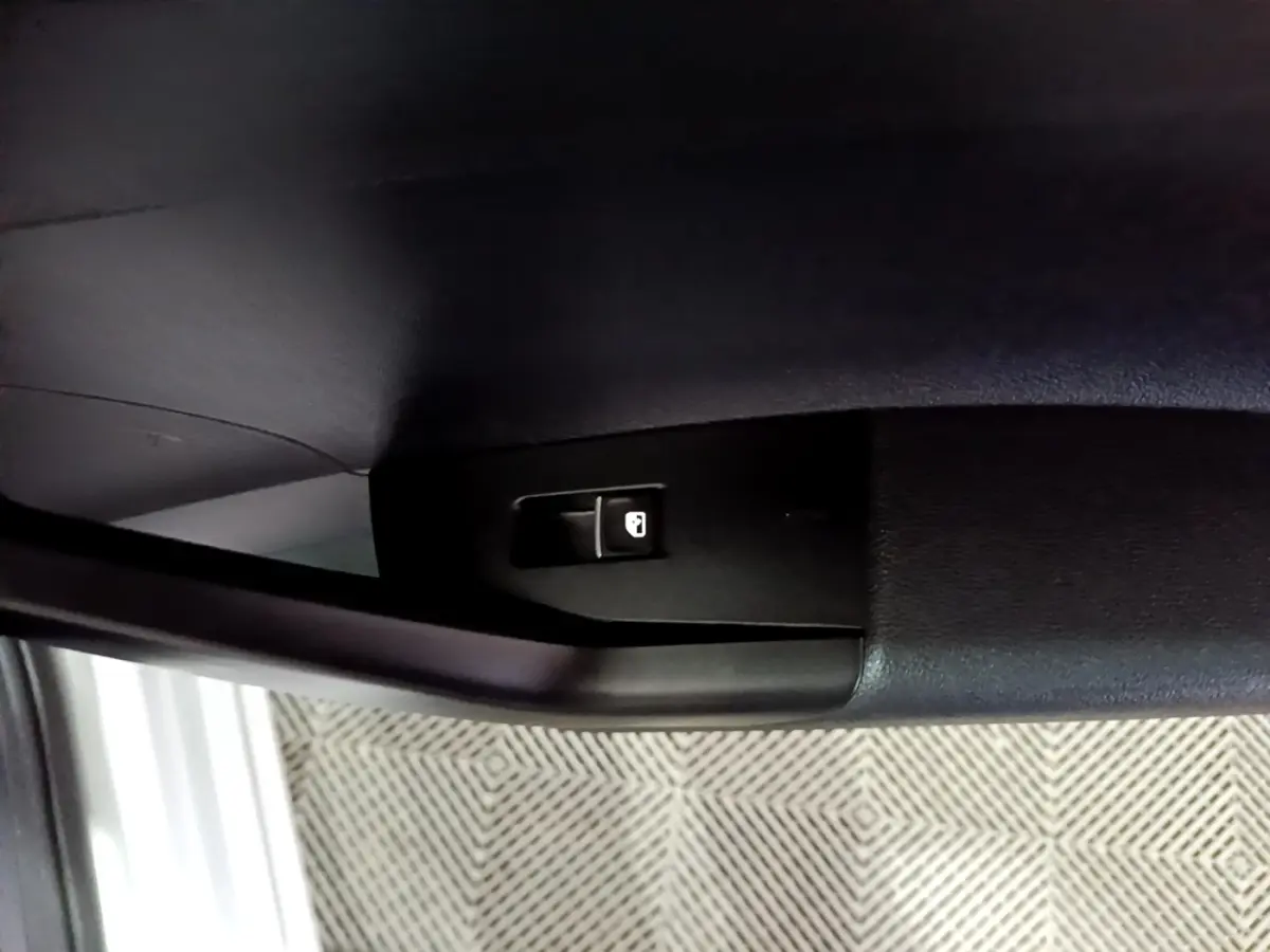 Gros plan sur le bouton de verrouillage de porte à l'intérieur d'une Volkswagen Taigo blanc, côté conducteur.