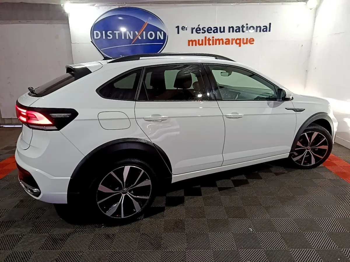 Vue latérale droite d’un Volkswagen Taigo blanc 2022 avec feux arrière allumés et jantes noires à motifs argentés.