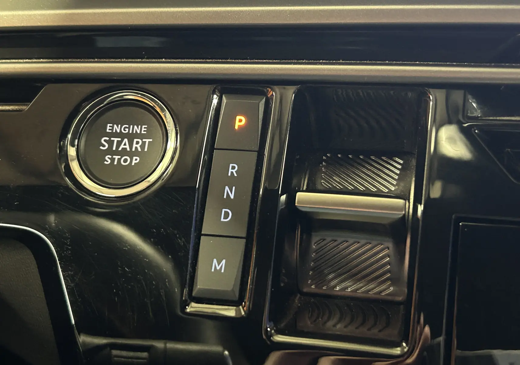 Gros plan sur la console centrale du Peugeot 5008 hybride 2025, avec bouton start/stop et sélecteur de boîte auto lumineux.