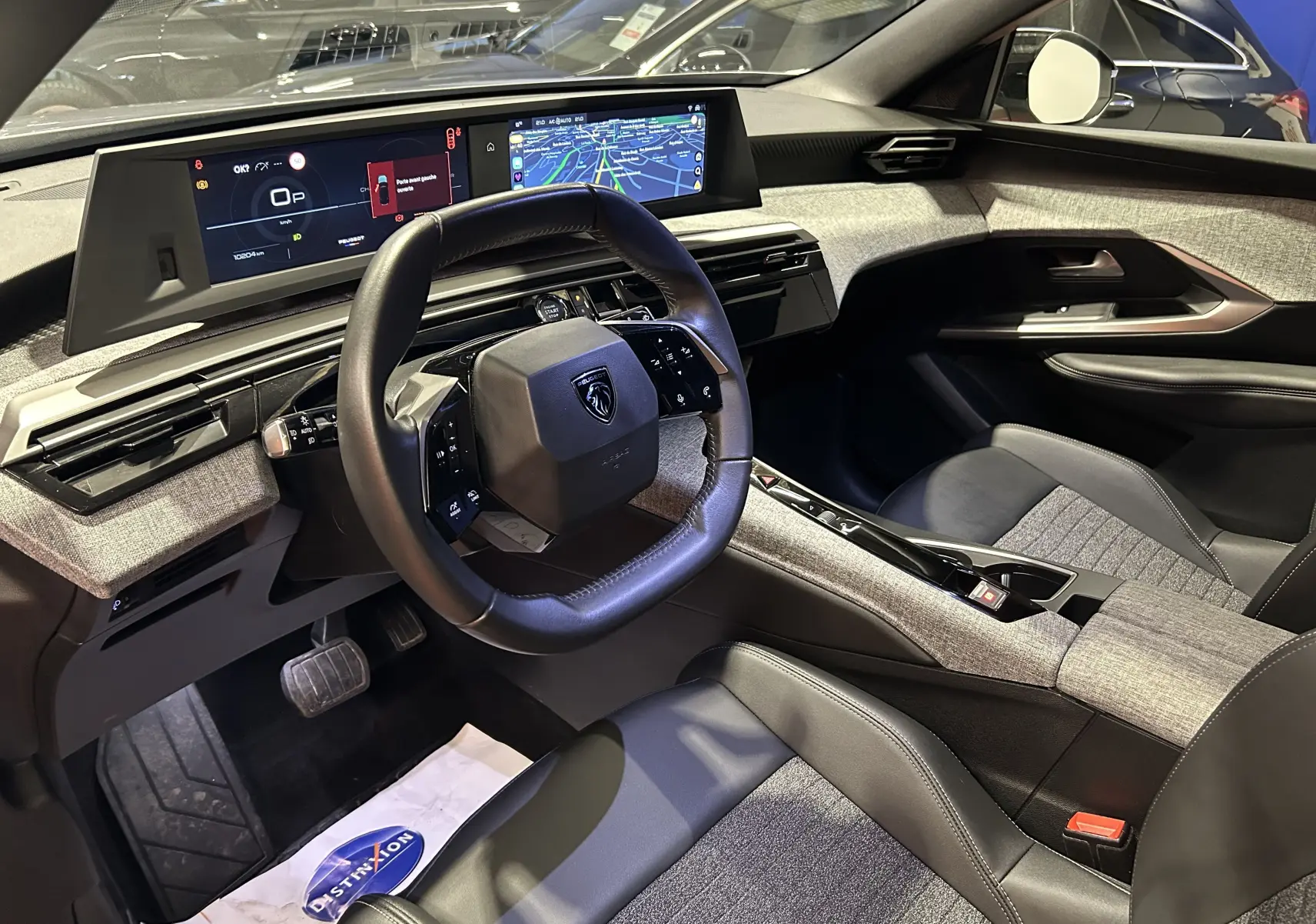Intérieur du Peugeot 5008 III Hybrid 145 en gris Artense, vue côté conducteur avec tableau de bord numérique et volant cuir.