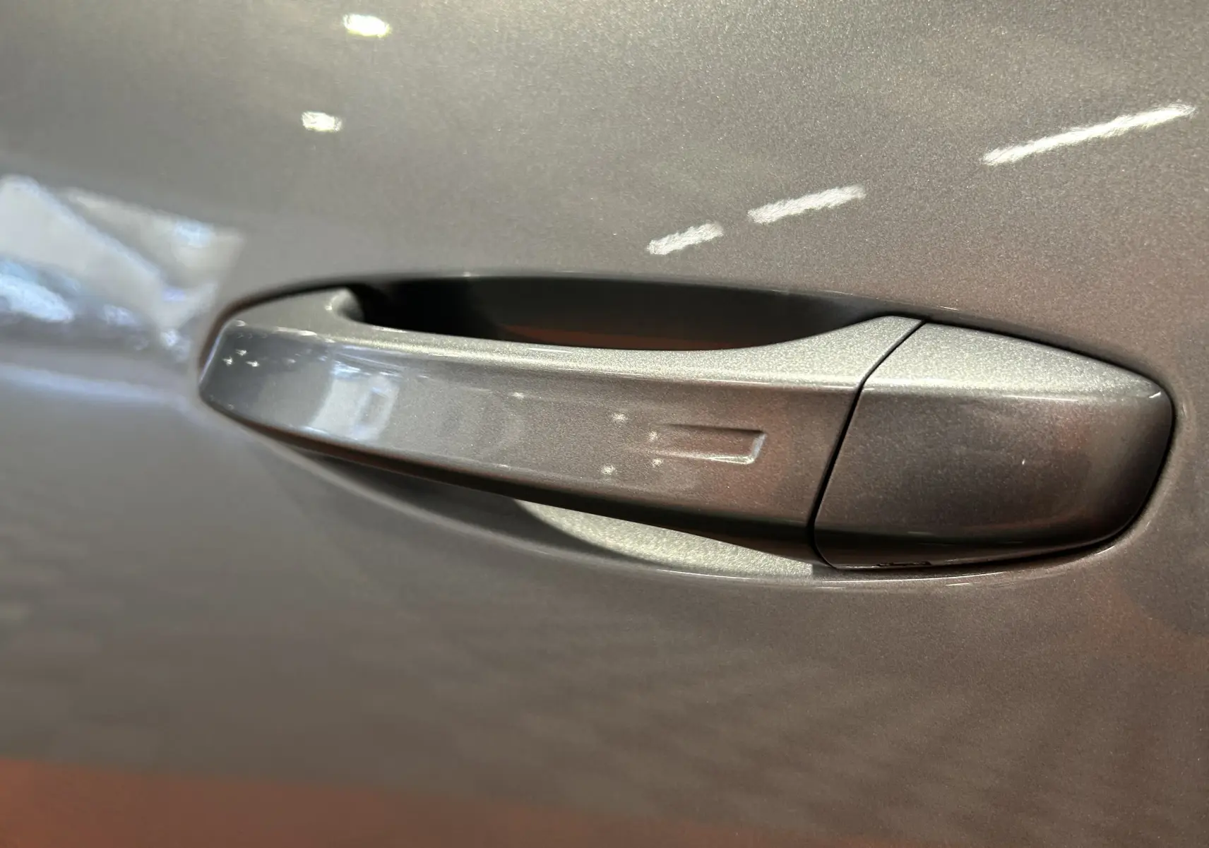 Poignée de porte gris Artense en gros plan sur Peugeot 5008 III Hybrid 2025, finition métallisée.