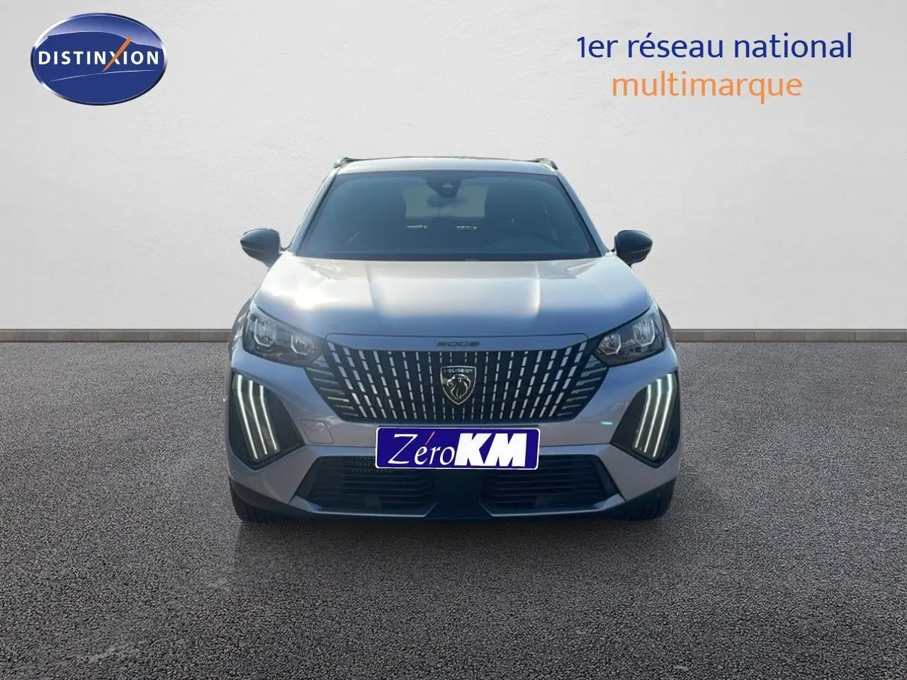 Vue frontale d'un Peugeot 2008 Hybrid gris Artense métal avec feux LED distinctifs allumés sur un sol gris.