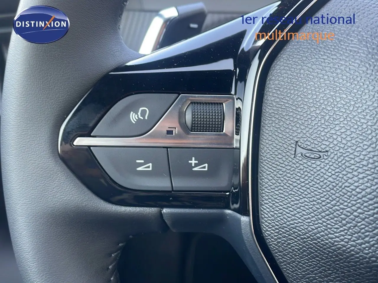 Gros plan sur les commandes du volant côté gauche du Peugeot 2008 gris Artense Hybrid 2025, boutons de volume et appel.