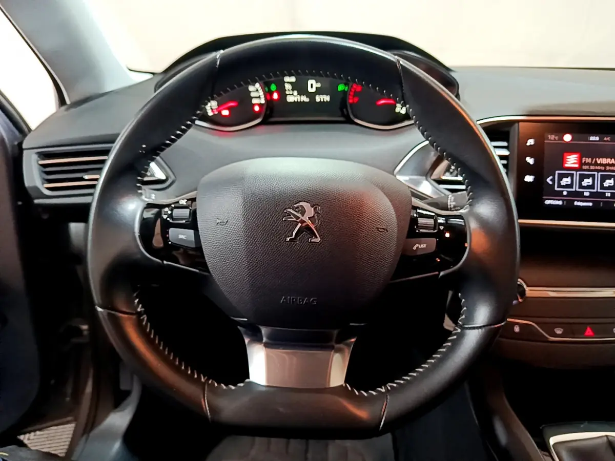 Volant cuir noir de Peugeot 308 2020 vu de face, avec tableau de bord numérique et écran tactile latéral allumé.