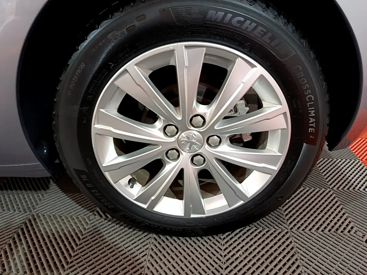 Gros plan sur la jante alliage argentée et pneu Michelin d'une Peugeot 308 gris clair, côté avant droit.
