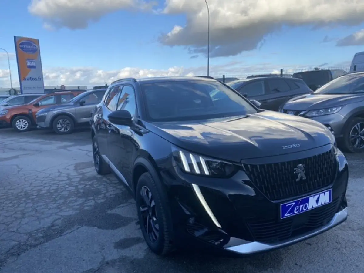 Peugeot 2008 noir vue 3/4 avant droit, avec calandre distinctive et feux LED verticaux allumés sur parking extérieur.
