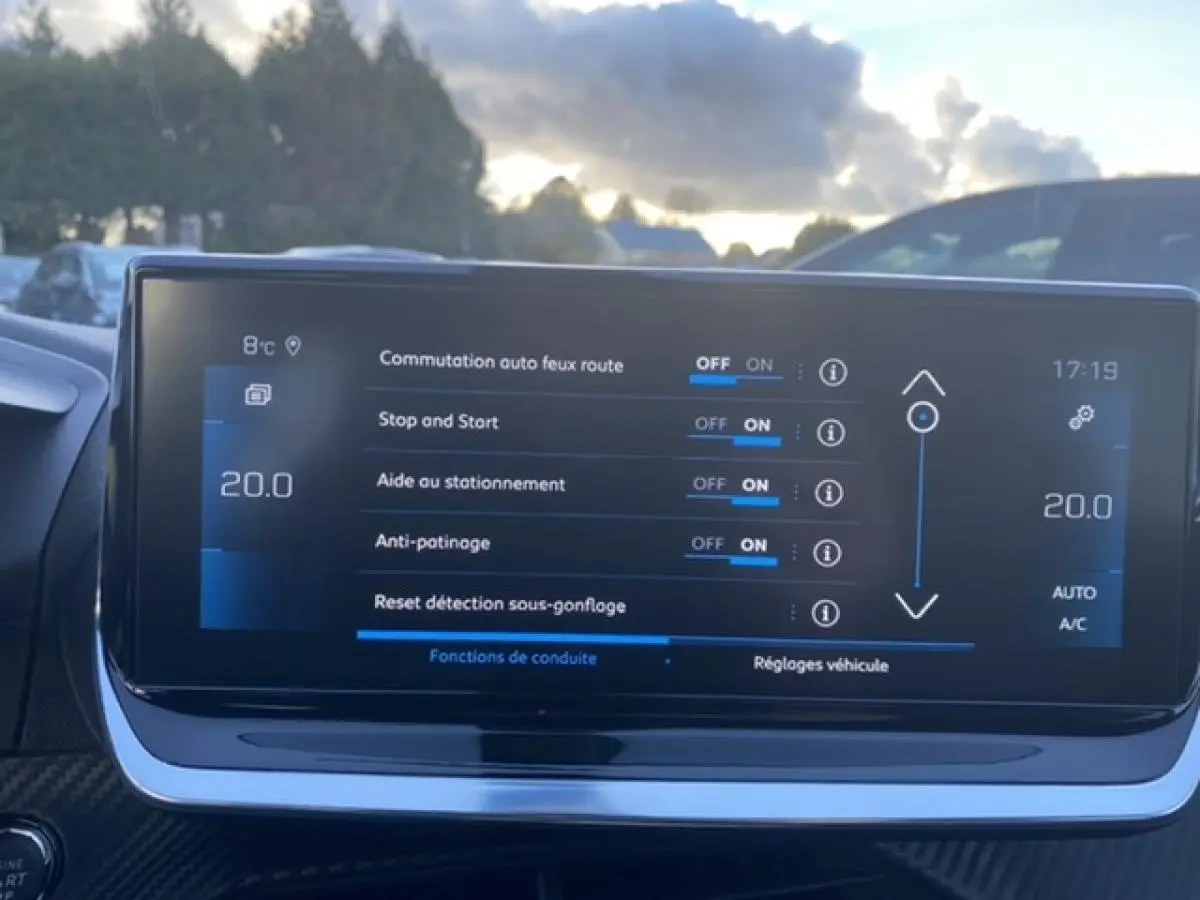Écran tactile du tableau de bord du Peugeot 2008 noir affichant les réglages d’aides à la conduite par temps clair.