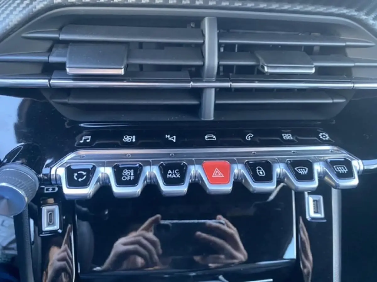 Gros plan sur la console centrale noire du Peugeot 2008 2021 avec boutons de climatisation et commandes tactiles.