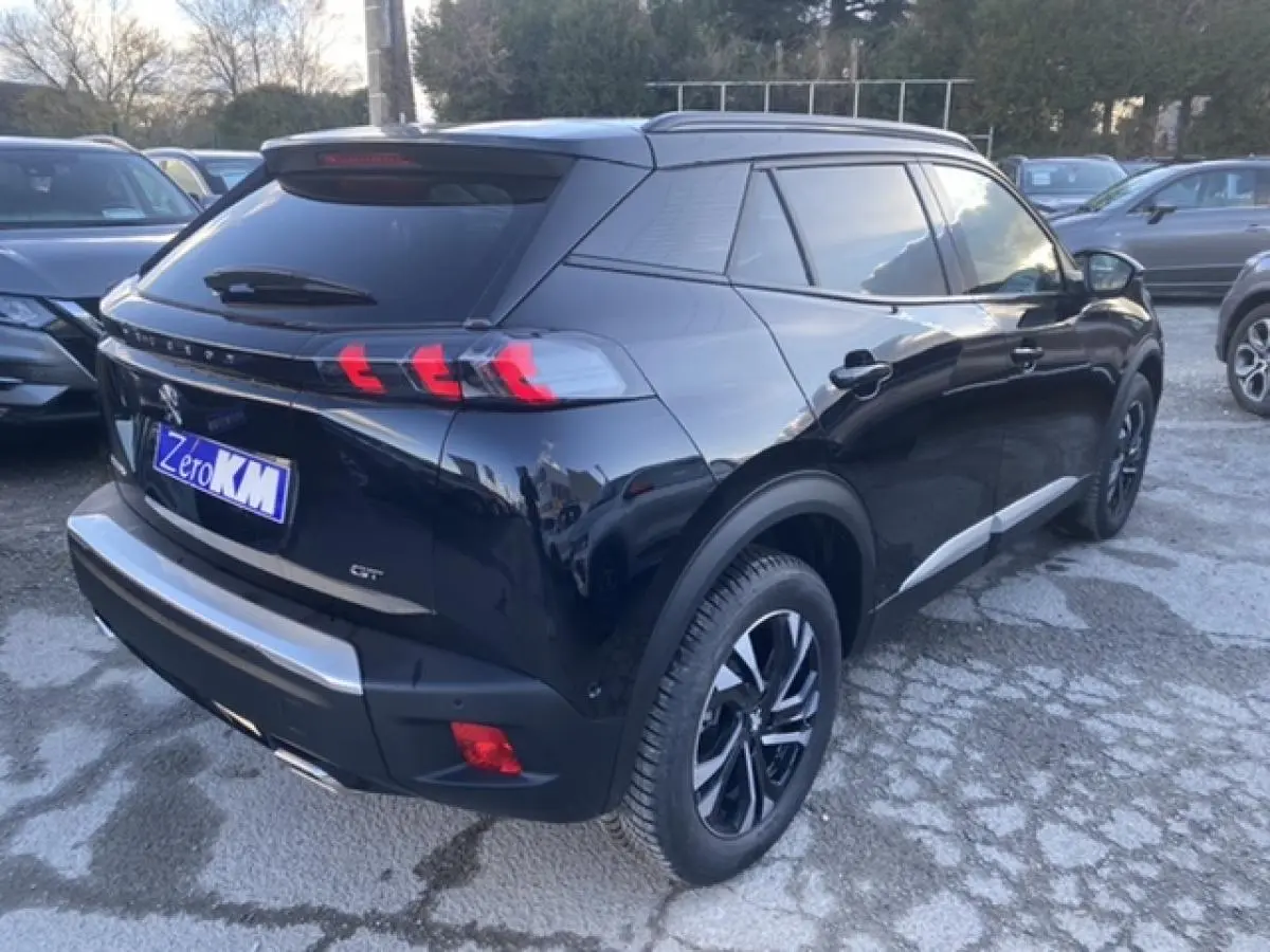 Vue 3/4 arrière droite d'un Peugeot 2008 noir brillant avec feux arrière à griffes et jantes alliage noires.