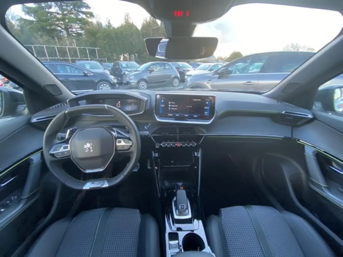 Intérieur Peugeot 2008 noir vue depuis l'arrière, tableau de bord moderne avec écran tactile et volant compact.
