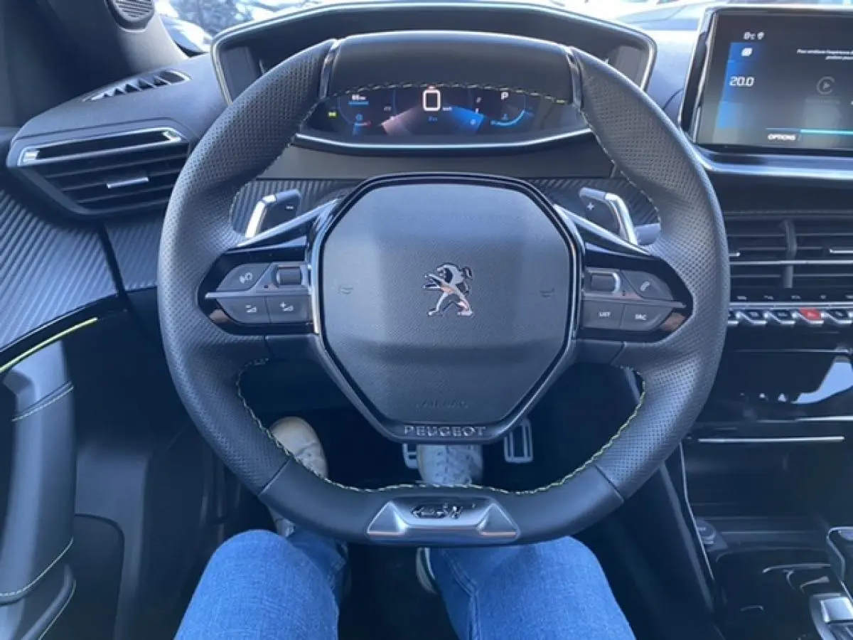 Vue intérieure centrée sur le volant noir du Peugeot 2008 2021, avec tableau de bord numérique et écran tactile à droite.