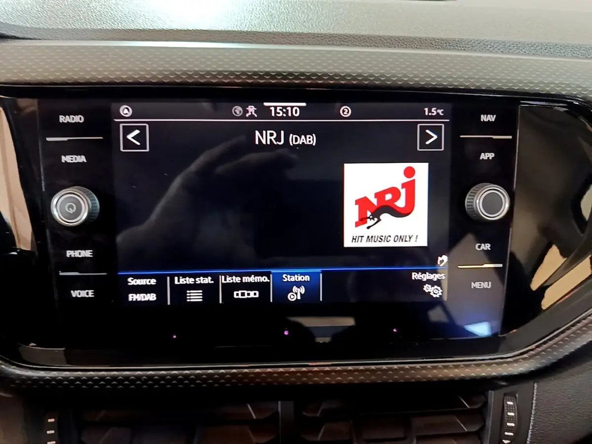 Écran tactile central du tableau de bord du Volkswagen T-Cross 2023 affichant la radio NRJ en mode DAB.