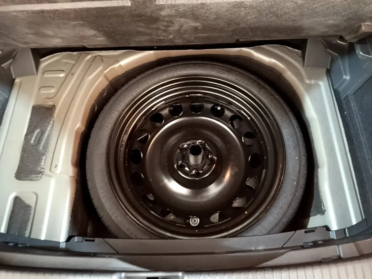 Roue de secours noire vue de dessus dans le coffre d’un Volkswagen T-Cross gris foncé 2023.