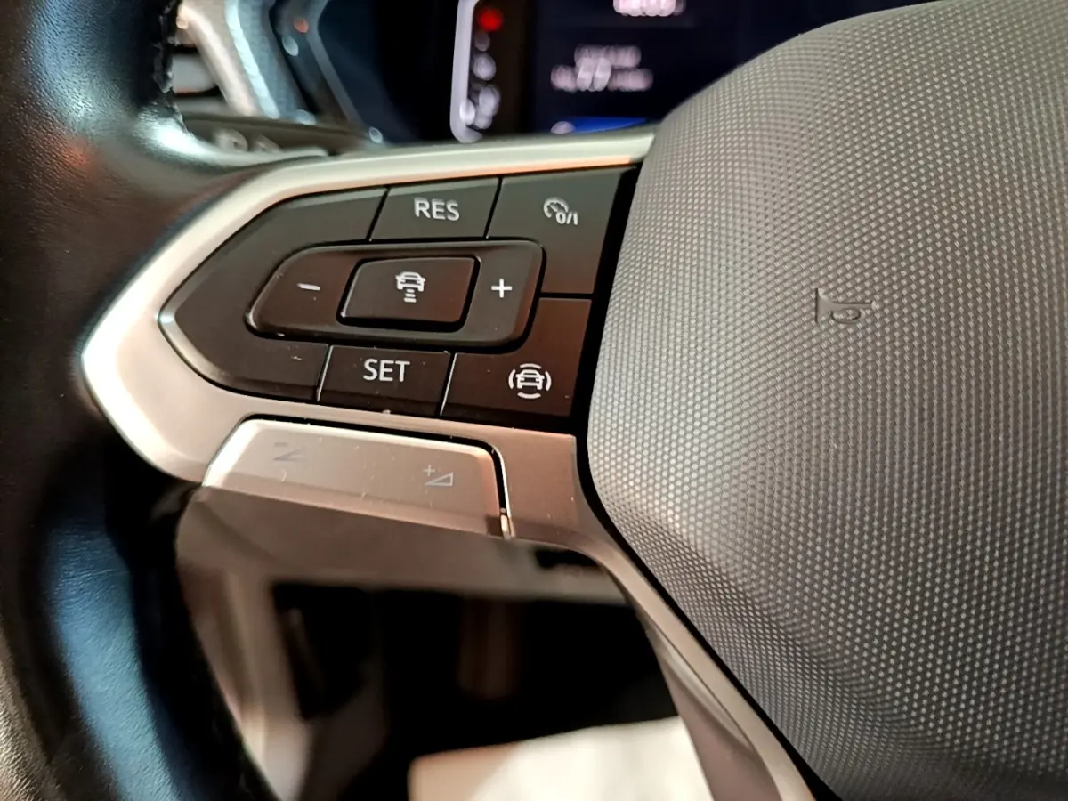 Gros plan sur le volant cuir multifonctions du Volkswagen T-Cross 2023, boutons de régulateur de vitesse visibles.