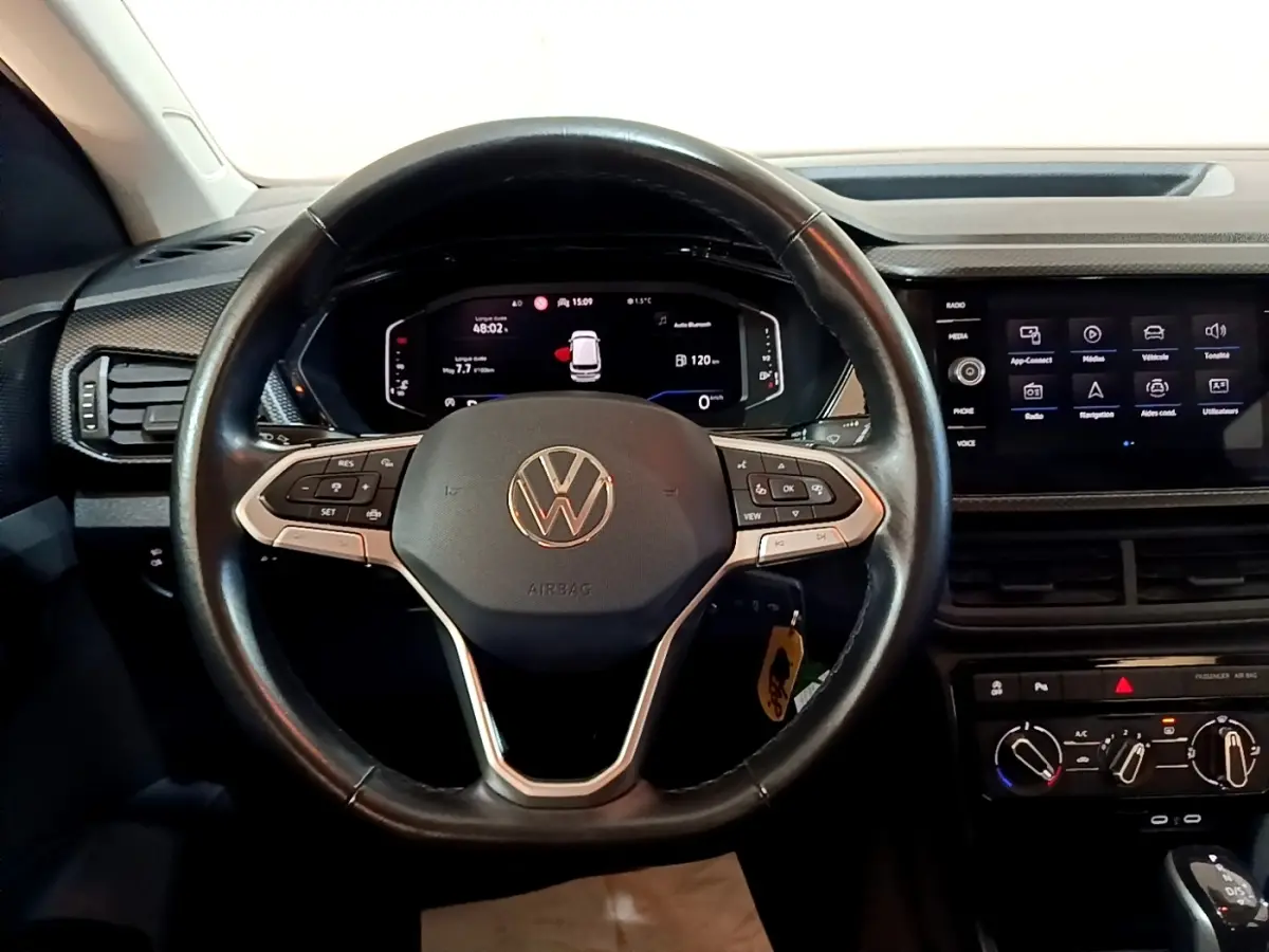 Vue rapprochée du volant cuir multifonctions noir du Volkswagen T-Cross 2023 avec tableau de bord digital et écran tactile central.