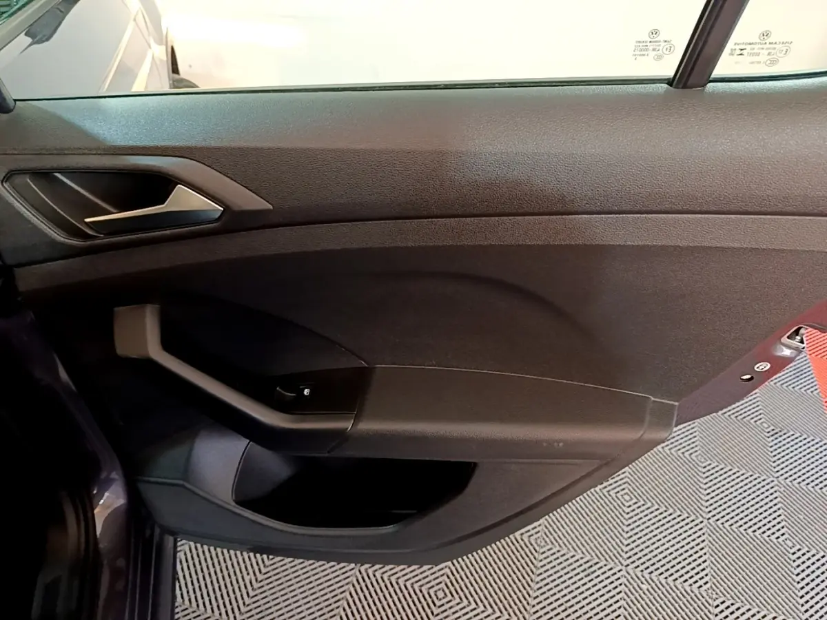 Vue intérieure côté gauche de la porte avant d’un Volkswagen T-Cross gris foncé avec poignée et commande de vitre.