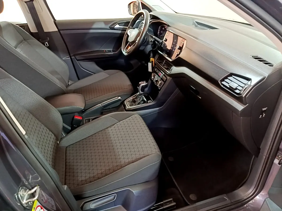 Vue intérieure côté conducteur du Volkswagen T-Cross gris foncé 2023, avec tableau de bord numérique et volant multifonctions cuir.