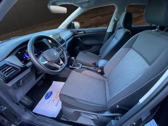 Vue intérieure côté conducteur du Volkswagen T-Cross 2025 noir, mettant en valeur les sièges tissu Life et le tableau de bord digital.