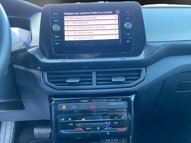 Vue rapprochée de la console centrale noire du Volkswagen T-Cross 2025, avec écran tactile et commandes climatisation tactile bi-zone.