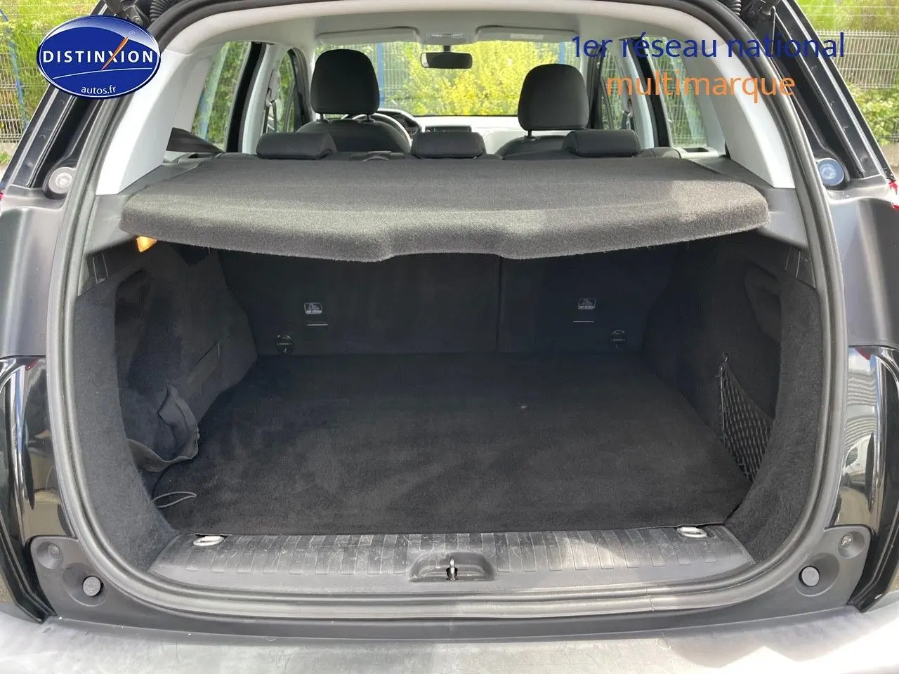 Coffre ouvert vu de l'arrière d'un Peugeot 2008 noir métal, montrant un espace de chargement propre et couvert.