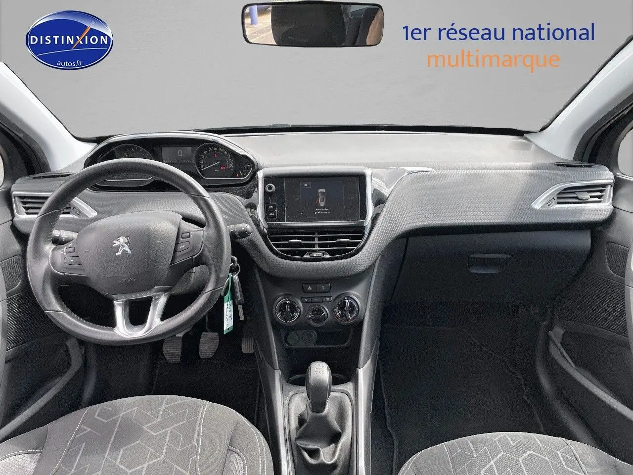 Vue intérieure avant du Peugeot 2008 noir métal de 2016, montrant le volant, la console centrale et les sièges gris.