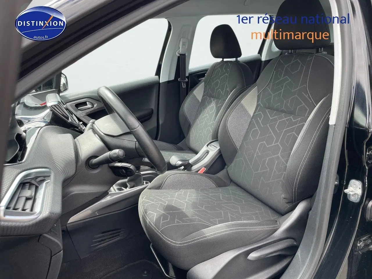 Vue intérieure côté conducteur du Peugeot 2008 noir métal 2016, mettant en valeur les sièges tissu gris et le tableau de bord.