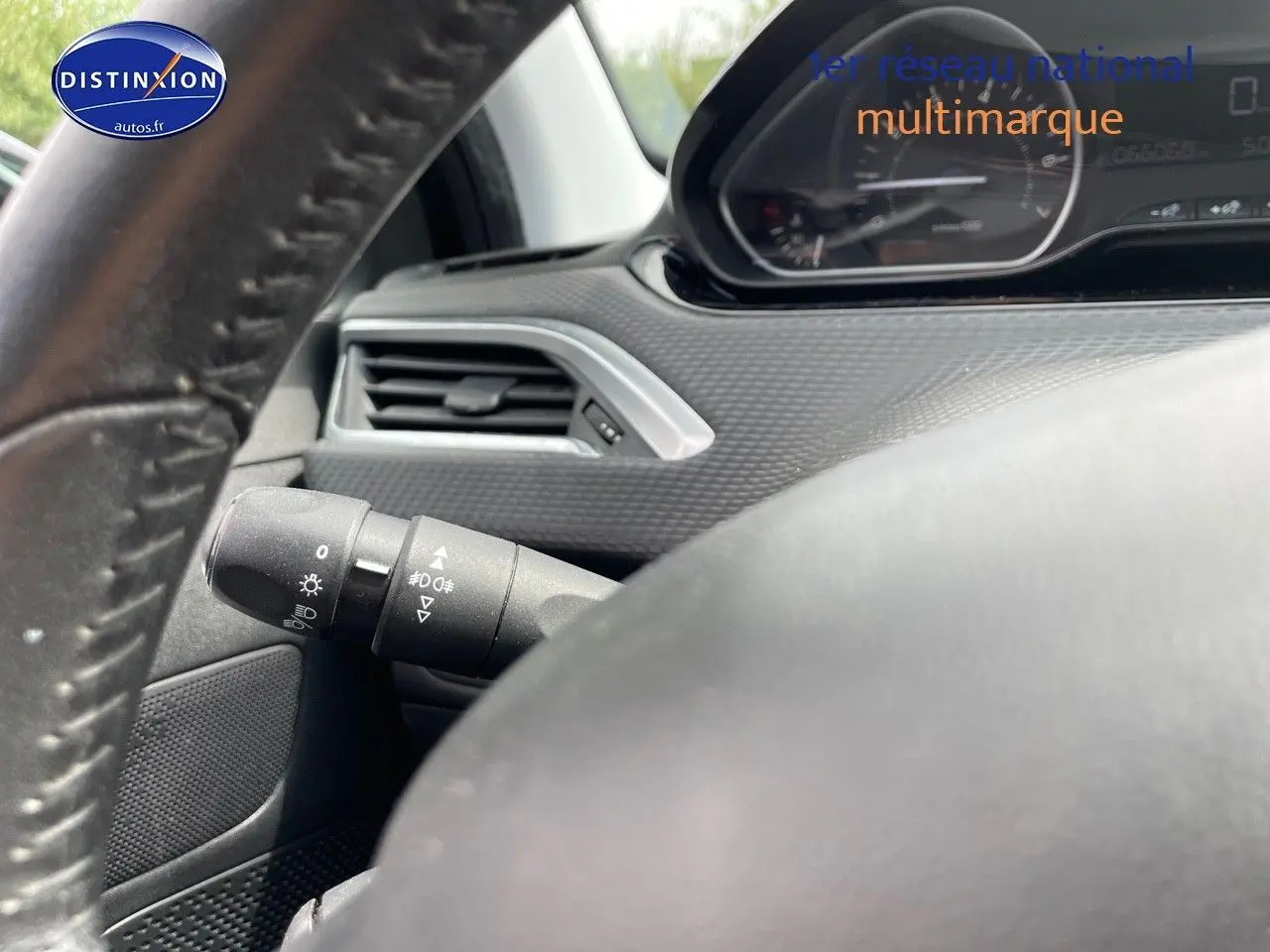 Gros plan sur le volant et la commande d'éclairage du tableau de bord d'une Peugeot 2008 noir métal, version 2016.