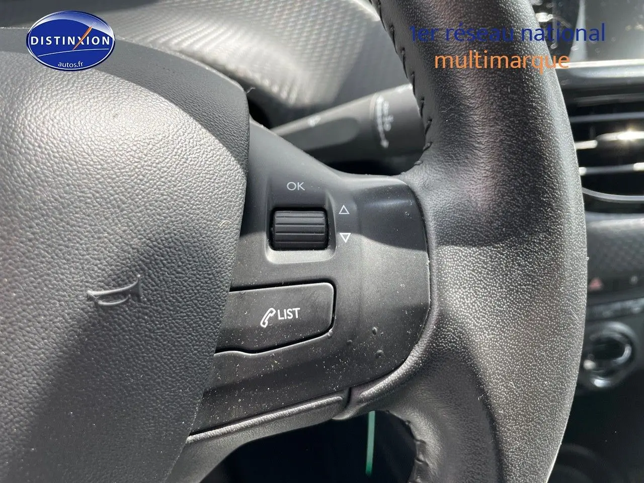 Gros plan sur le volant noir texturé du Peugeot 2008 1.2 PureTech 82ch Style, montrant les commandes intégrées côté gauche.