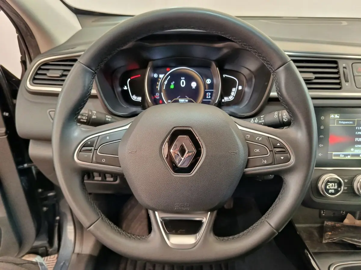 Vue intérieure centrée sur le volant cuir noir du Renault Kadjar 2022 avec tableau de bord numérique et écran tactile.