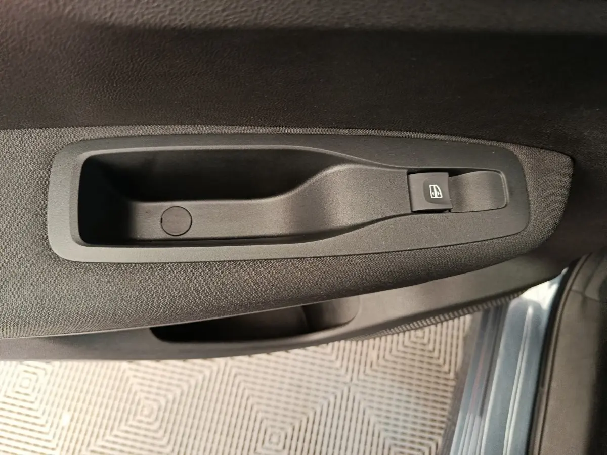 Poignée intérieure noire avec bouton de lève-vitre sur la porte côté conducteur du Renault Kadjar gris foncé 2022.