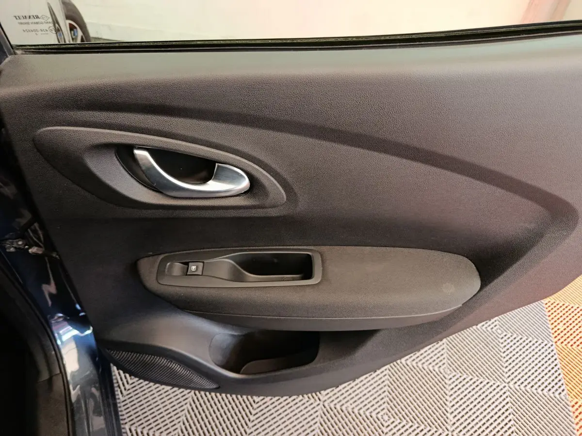 Gros plan sur la porte intérieure côté gauche du Renault Kadjar gris foncé, avec poignée et commande de vitre.