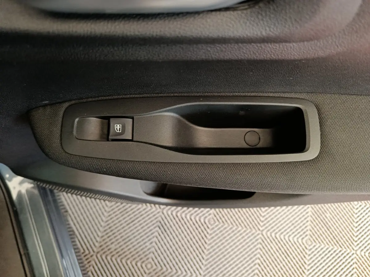 Poignée de porte intérieure noire côté gauche du Renault Kadjar Business 2022 avec bouton de commande de vitre électrique.