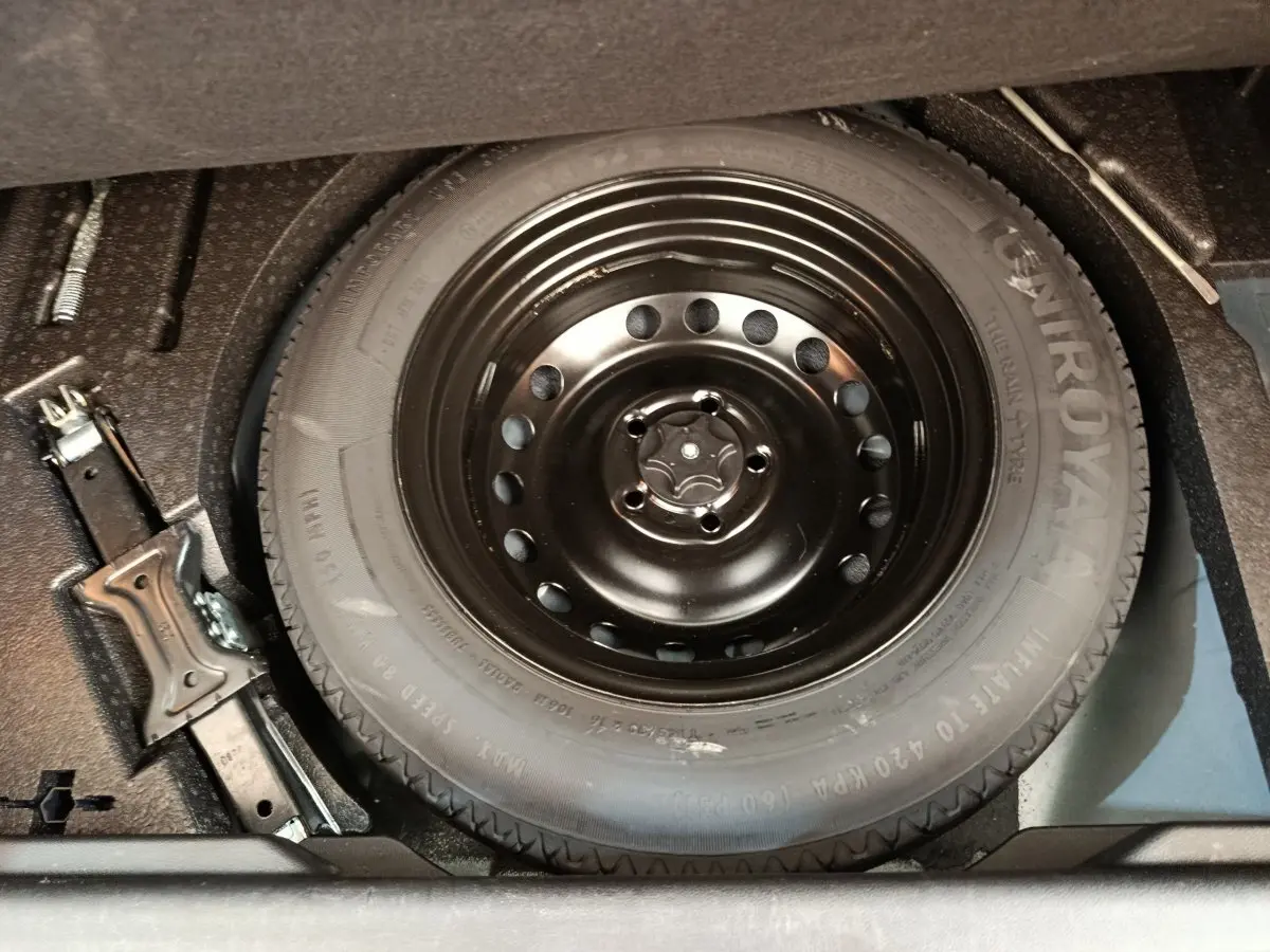 Gros plan sur la roue de secours noire et le cric dans le coffre d'un Renault Kadjar gris foncé 2022.