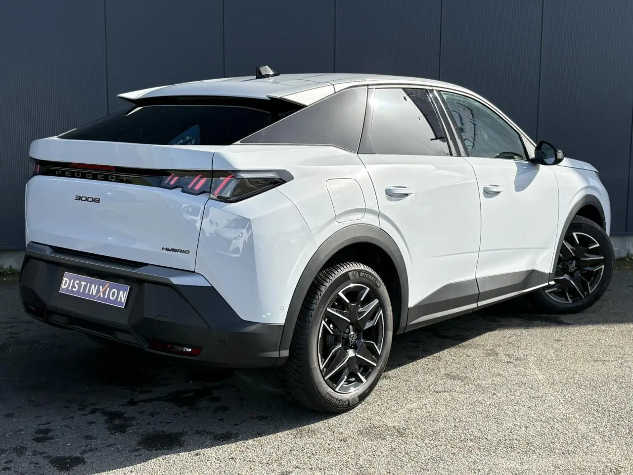 Vue 3/4 arrière droite du Peugeot 3008 Hybrid blanc Okenite avec jantes alliage noires et feux arrière LED 3 griffes.