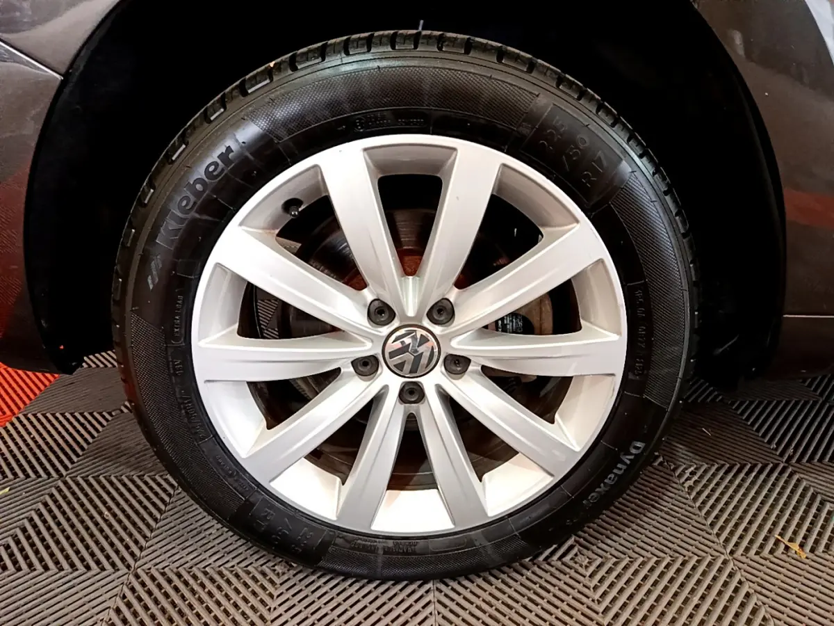 Gros plan sur la roue avant gauche du Volkswagen Sharan marron, mettant en valeur la jante alliage argentée et le pneu Kleber.